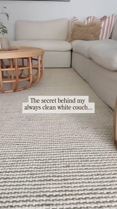 A mom spraying protectME on her couch, showing how she keeps her white couch always clean because of protectME