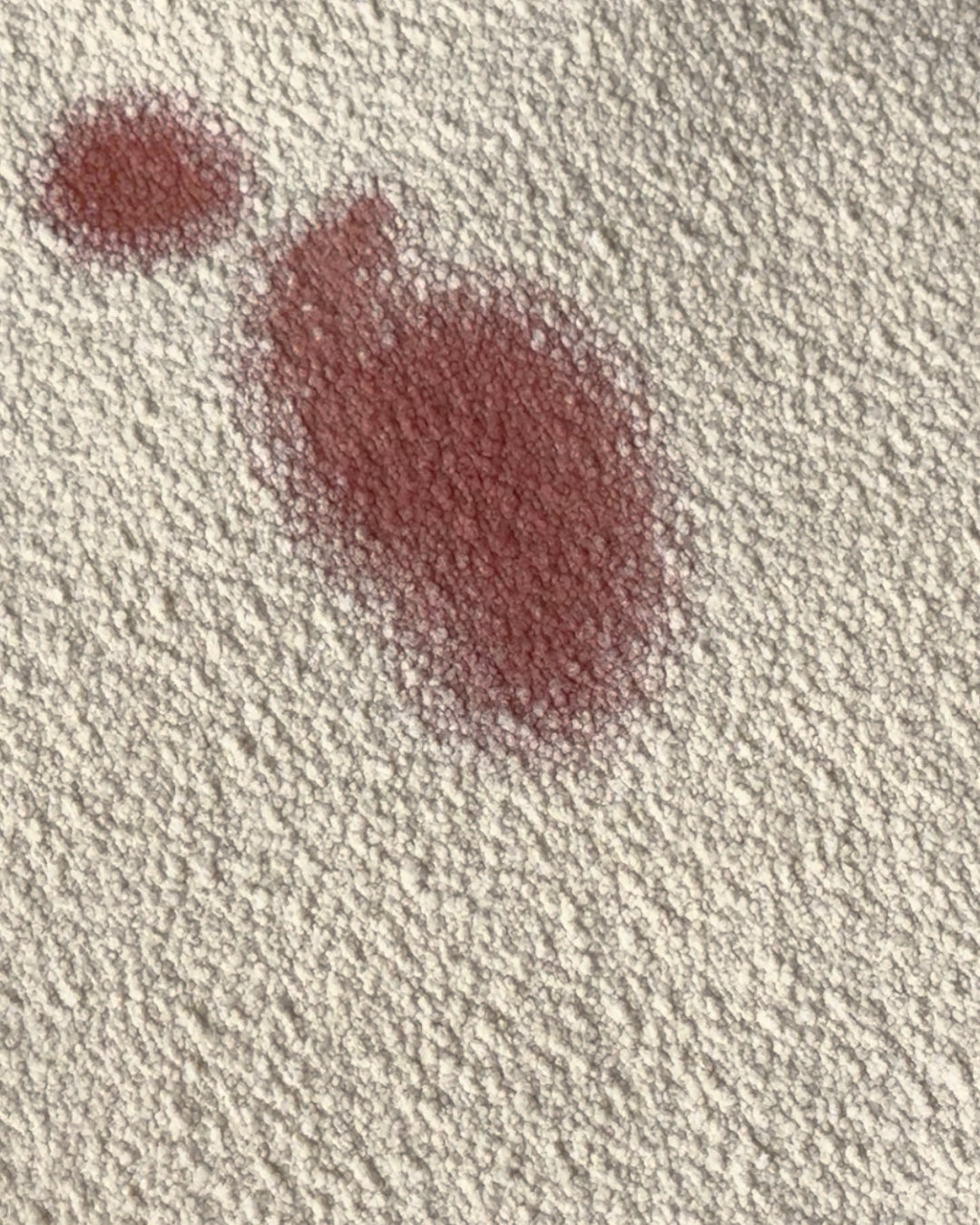 A wine spill that has stained the  textured bouclé fabric. This demonstrates the "before" effect of protectME on fabric, showing the importance spill protection.