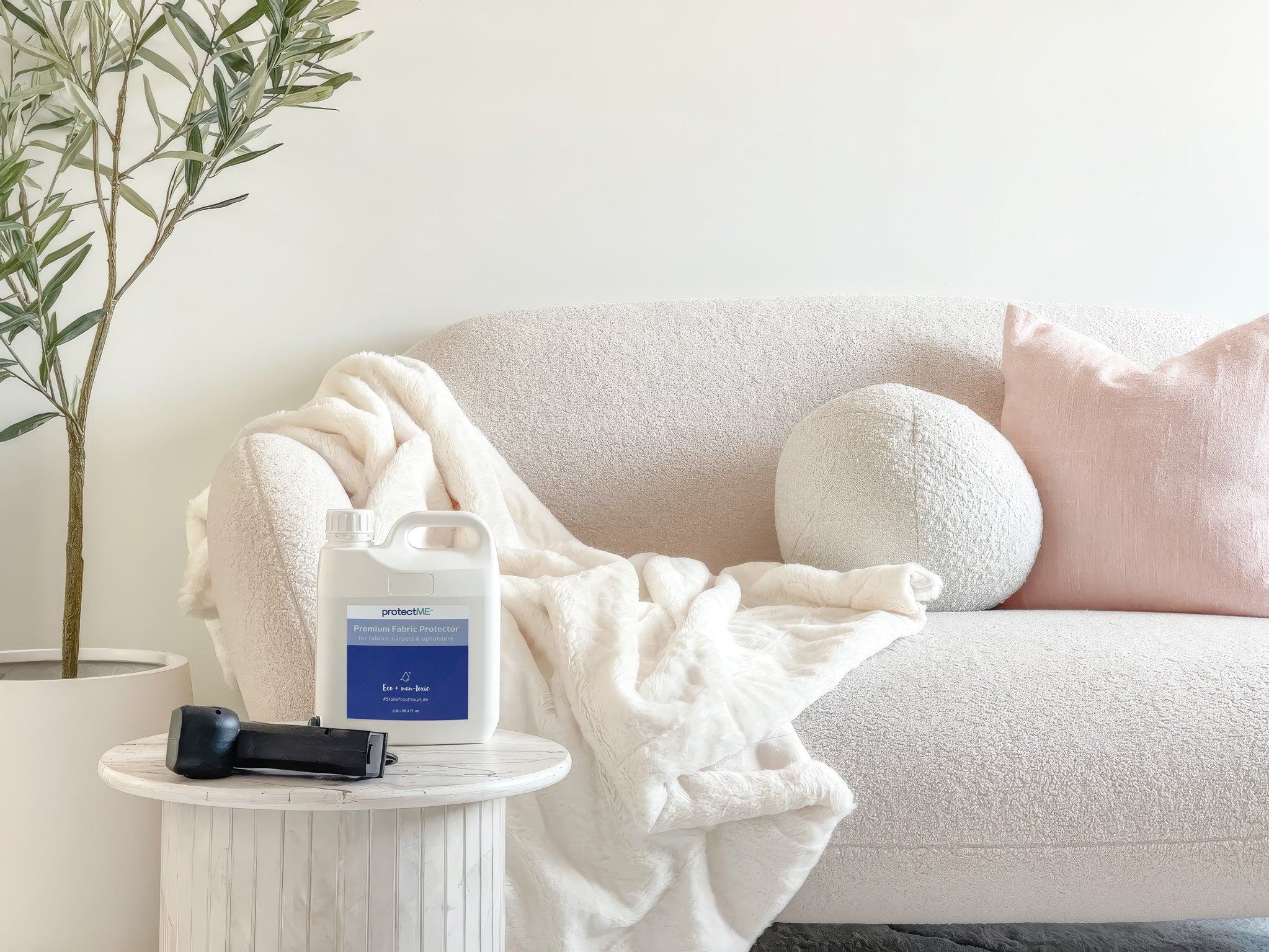 protectME bottle on a side table next to a sofa with a blanket and plant