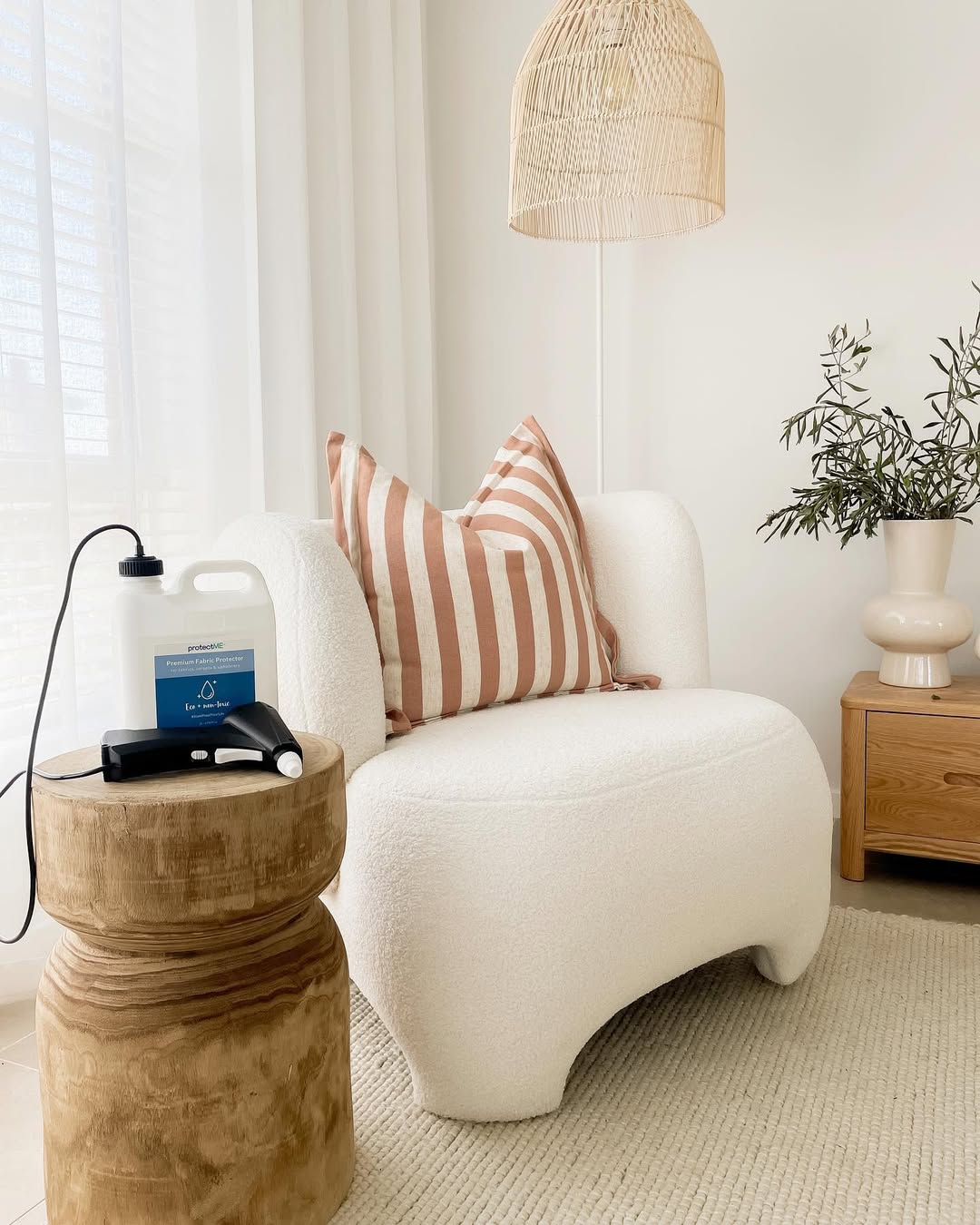 White armchair with striped cushions in a living room setting with a protectME bottle on the table beside the chair.