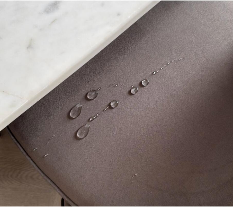 Water droplets on a gray surface with a marble countertop in the background after use of protectMe